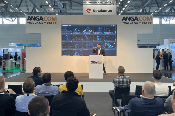 Witbe presentation at ANGA COM 2025 on the Innovation Stage, showcasing real-time video monitoring on actual devices, with an engaged audience watching.