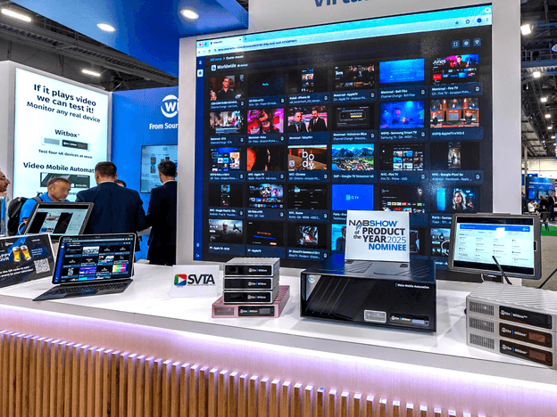 Witbe trade show booth showcasing Witbox devices and real-device video monitoring on a large screen.